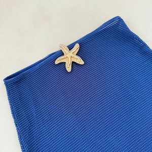 Detail of blue mesh knit fabric featuring a decorative gold starfish metal accessory
