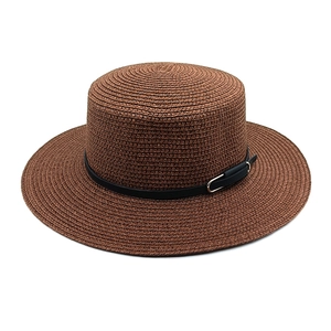 Détail d'un chapeau de paille marron avec ceinture en cuir noir et boucle en métal argenté
