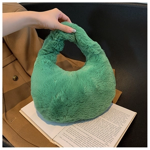 Close-up of green fuzzy plush handbag with short handle on an open book background