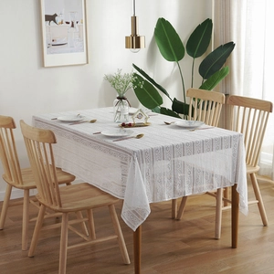 Detailed close-up of white hollow stripe lace tablecloth on a wooden dining table