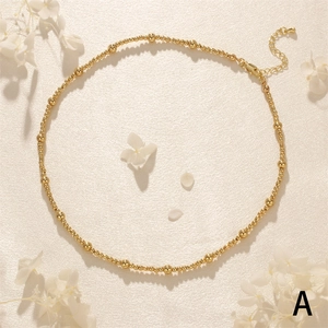 Close-up of golden beaded necklace with lobster clasp and adjustable chain on petal background