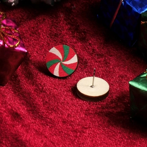 Detail of wooden peppermint swirl stud earrings on festive red velvet background