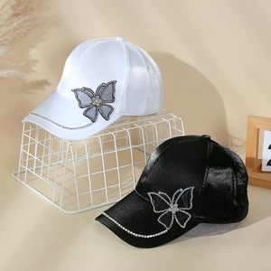 Detail of satin baseball caps with rhinestone butterfly and diamond-studded brim