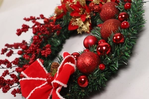 Close-up of a Christmas wreath featuring red berries, golden flowers and a velvet bow