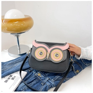 Detailed view of grey owl-shaped PU leather crossbody bag with pink accents on jeans