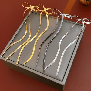 Vue détaillée de boucles d'oreilles nœuds dorées et argentées sur un écrin gris