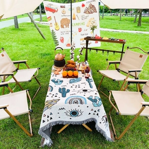 Bohemian picnic blanket with cactus pattern and fringe detail on a camping table