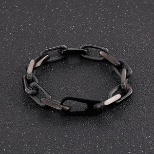 Macro detail of black titanium steel chain link bracelet on textured dark background