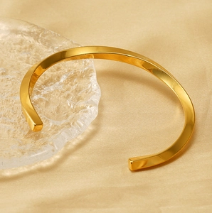 Vue détaillée d'un bracelet manchette torsadé plaqué or sur un tissu en soie élégant