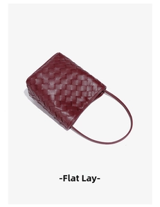 Vue à plat d'un sac seau bordeaux tressé à la main avec de fines lanières de cuir