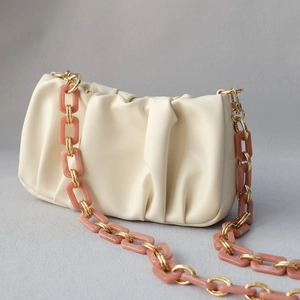 Detail of beige pleated cloud bag with chunky gold and resin chain link strap