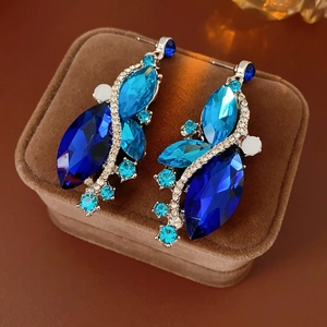 Macro shot of vintage silver earrings with blue and white crystals on brown velvet case