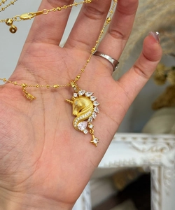 Detail of 18k gold-plated unicorn pendant with cubic zirconia stones on the palm