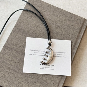 Vue détaillée du pendentif peigne argenté créatif avec finition lisse et cordon en cuir