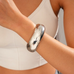 Close-up of a silver wide cuff bracelet with hammered metal texture on model's wrist
