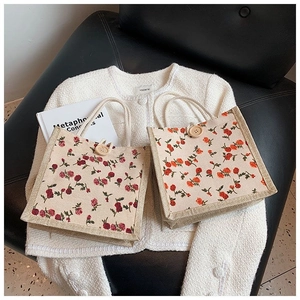Detail of floral canvas tote bags with woven handles and decorative wooden buttons