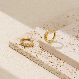 Close-up of golden S925 sterling silver hoop earrings with inset diamonds on stone