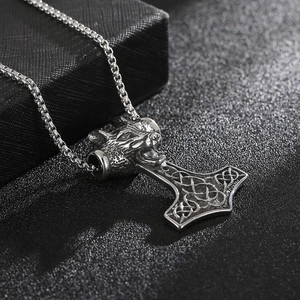 Macro detail of punk wolf head Thor's hammer pendant in silver steel with box chain