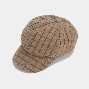 Detailed top view of a brown plaid newsboy cap showing tweed fabric texture and button top