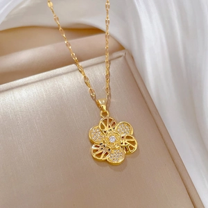 Elegant gold flower necklace with crystal petals and cubic zirconia on a warm background