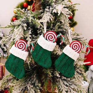 Three green knit Christmas stockings with candy canes on a snowy tree branch