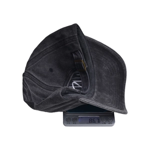 Close-up van een zwarte distressed baseballpet die 86,7 g weegt op een digitale weegschaal.