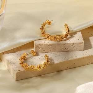 Primer plano de pendientes florales dorados en soportes de piedra y seda elegante