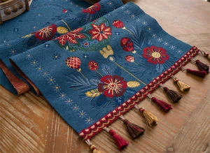 Close-up of blue embroidered table runner with floral patterns and decorative tassels