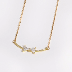 Detail shot of golden bow necklace pendant with sparkling zircon and fine cross chain