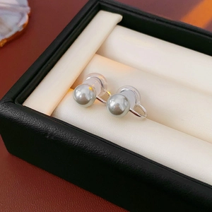 Close-up of silver-tone U-shaped pearl ear clips with protective silicone pads