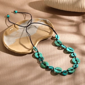 Detail of handmade turquoise bead necklace with adjustable brown cord on ceramic plate