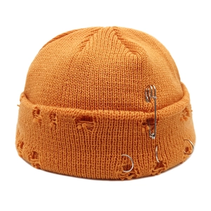 Close-up of bright orange knit miki hat featuring street style torn holes and metal pins