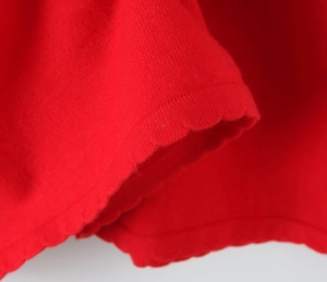 Detail of red knit dress showing the delicate scalloped edge and fine texture