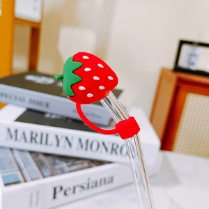 Close-up of glass straw featuring a cute red strawberry silicone dust cap and holder