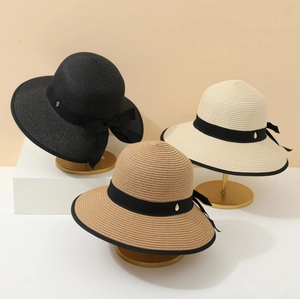 Three elegant French straw sun hats with black bows and golden metal details