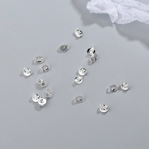 S925 sterling silver earring backs in platinum finish scattered on grey background