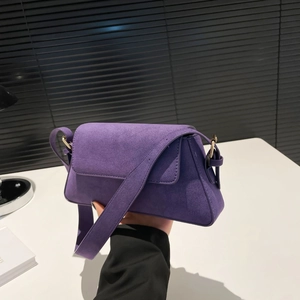 Close-up of purple suede shoulder bag with gold hardware and wide strap detail