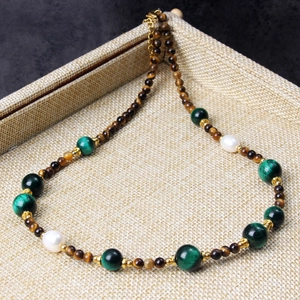 Macro detail of tiger eye and green agate beaded necklace with white pearls and gold clasp