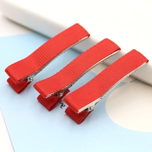 Detailed view of three red ribbed ribbon duckbill hair clips on a blue card