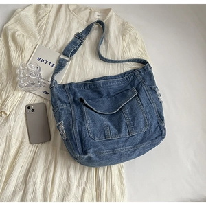 Détail du sac bandoulière en jean bleu avec franges vieillies et grande poche frontale