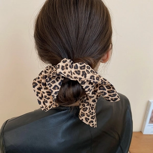 Gros plan d'un chouchou léopard marron en tissu noué sur un chignon de cheveux bruns