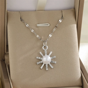Détail du pendentif soleil argenté avec perle blanche et strass brillants sur l'écrin