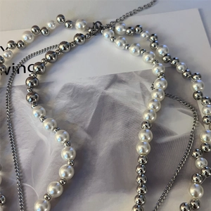Elegant multi-layered necklace with white pearls and silver beads on aesthetic background