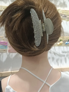 Detail of silver rhinestone bow hair claw clip worn on model's hair for elegant styling
