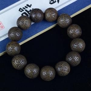 Macro detail of dark Phoebe zhennan wood beads with gold Six-Syllable Mantra engraving