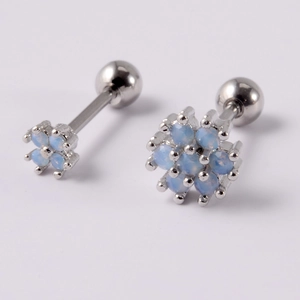 Detailed macro view of silver flower cartilage studs with blue synthetic opal and screw balls