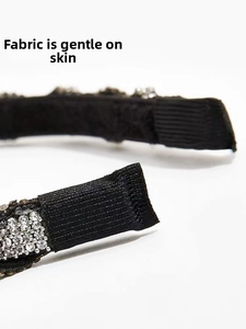 Detalle macro de los extremos de la diadema forrados en tela negra con pedrería de lujo