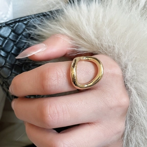 Close-up of a chunky golden geometric open ring with polished finish on model hand