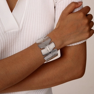 Detailed view of silver stainless steel leaf textured cuff bracelet on model wrist