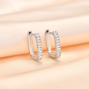 Silver geometric earrings with pavé white zircon stones on silk fabric background